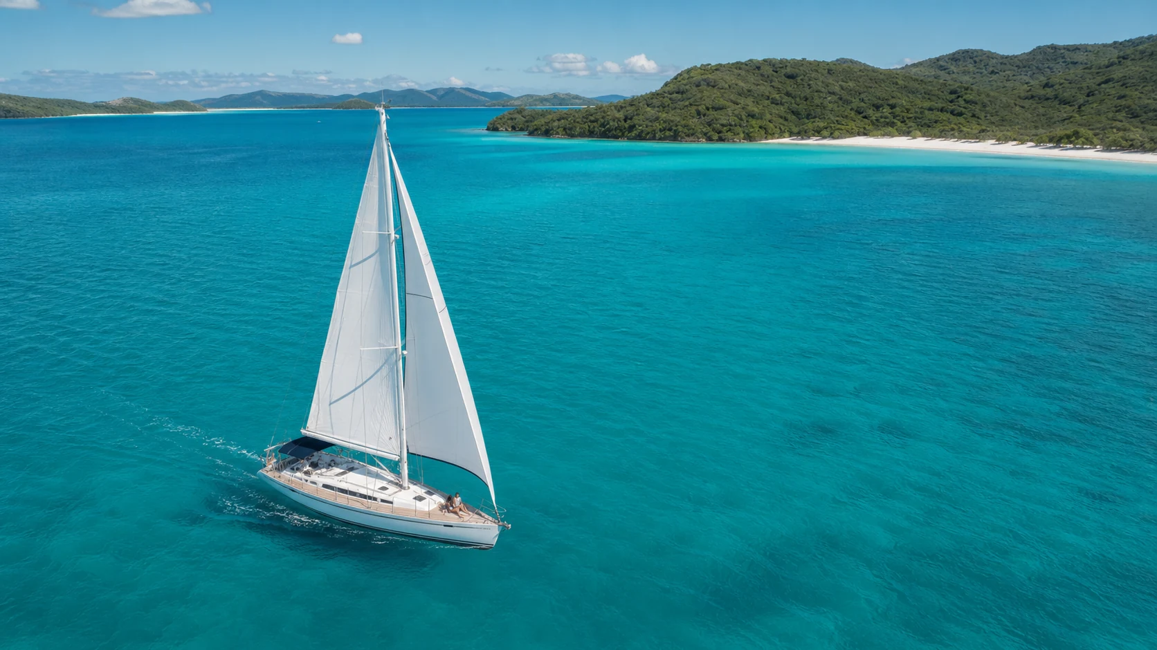 Voilier sur une mer turquoise bordée d’îles verdoyantes dans les Whitsundays