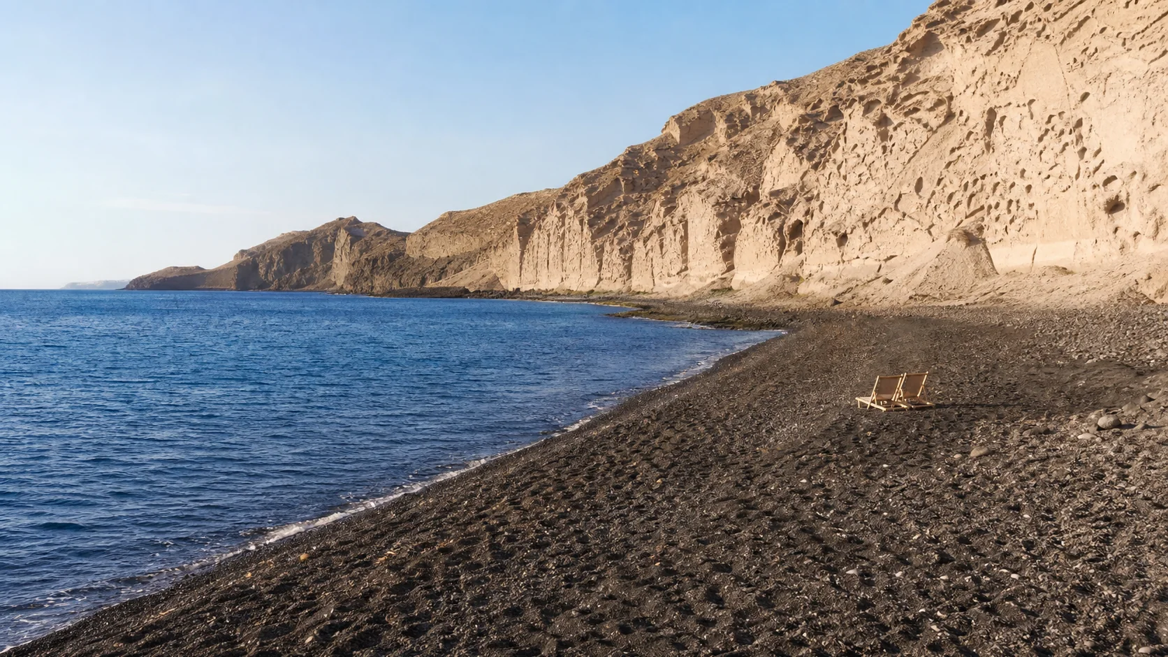 Plage volcanique noire au pied de falaises claires sur la côte de Santorin